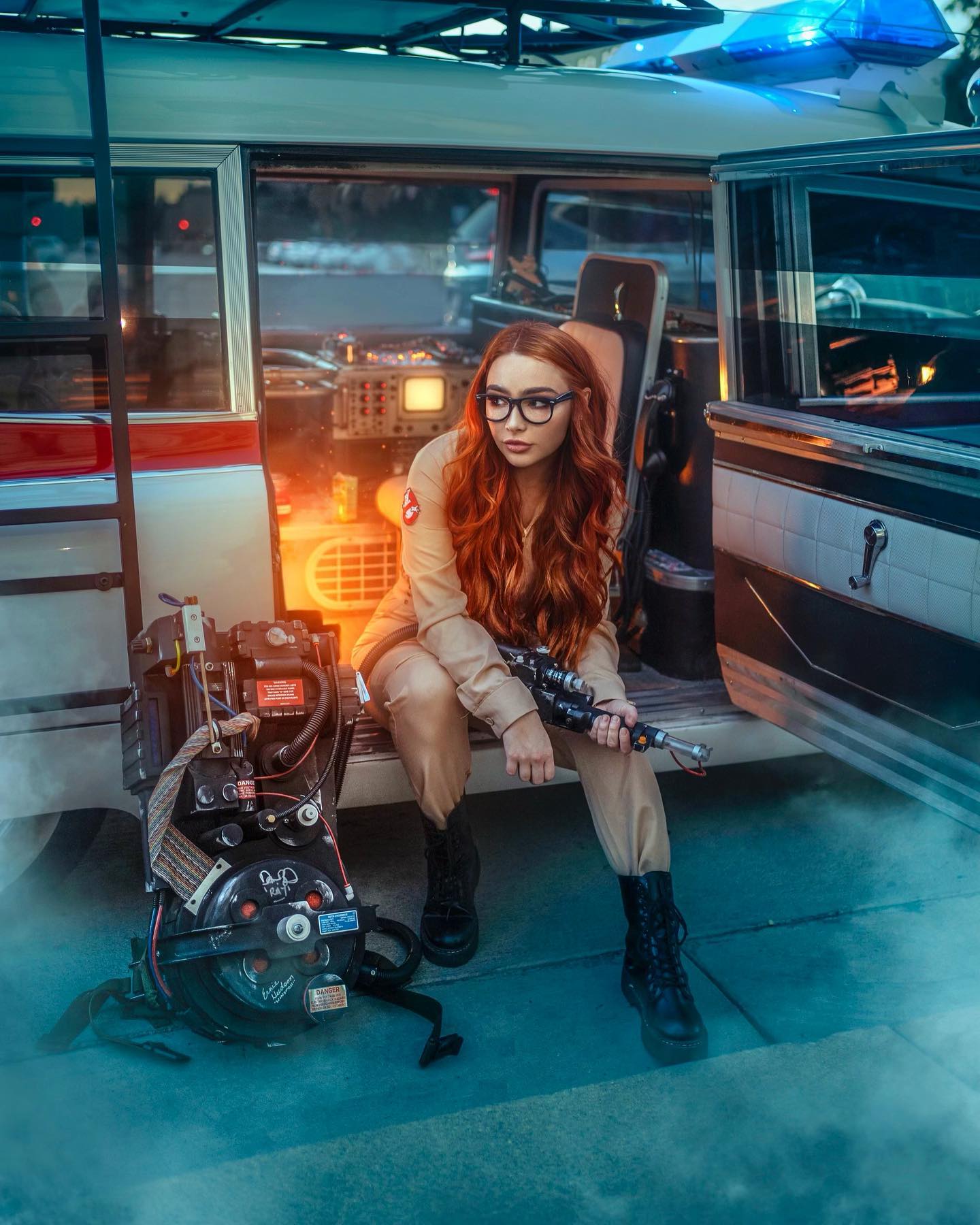 Woman in a Ghostbusters costume inside the Ecto-1
